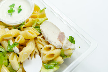 Penne pasta in a mayonnaise dressing with bacon pieces topped with parsley rubbed cooked chicken breast pieces