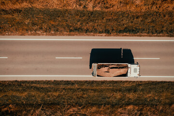 Aerial shot of freight truck transporting sand as construction material, top down drone pov