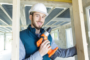 portrait of young male carpenter holding cordless power tool