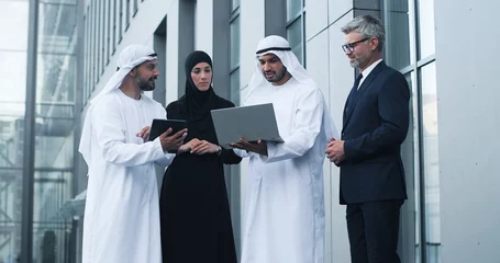 Papier Peint photo Lavable Abu Dhabi Waist up portrait view of the serious successful business people looking at the laptop screen and discussing something while standing at the street near the office