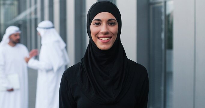 Waist up portrait view of the happy businesswoman wearing head scarf standing at the street at the dinner break and smiling near her office center. Business people concept