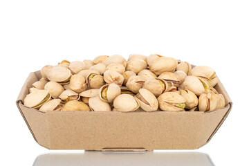 Many unpeeled pistachios in a paper box, close-up, isolated on white.