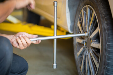 Mechanic changing car tire with wheel wrench, Technician fixing tire with wrench, Repairing and maintenance in garage concepts