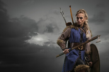 Beautiful female viking woman warrior in battle with ax and bow with arrows. Amazon fantasy blonde hair sexy girl - obrazy, fototapety, plakaty
