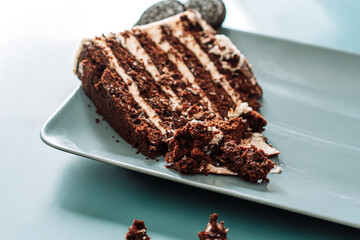 Piece of puff chocolate cake with cookies on square plate