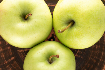 Three ripe sweet apples on a clay dish, close-up, top view.