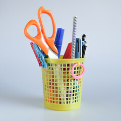 Set of stationery items in basket on background.