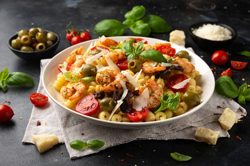 King prawn pasta salad with marinated green olives, cherry tomatoes and parmesan cheese shavings. Healthy food.