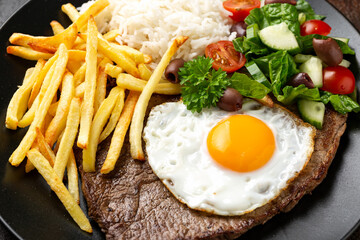 Portugal dish Bitoque made from beef steak with a fried egg, rice, french fries and vegetables