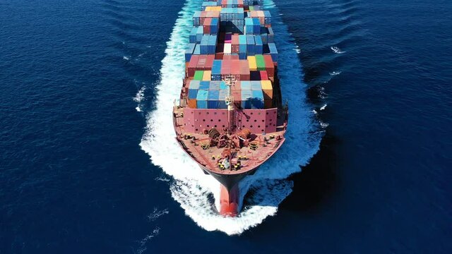 Aerial drone video of huge container carrier tanker ship front bow cruising deep blue open ocean sea