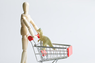 A lonely anthropomorphic mannequin is carrying a cute funny dinosaur in a supermarket cart. The...