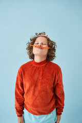 Little boy joking while holding pencil over mouth