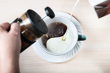 milk and black coffee are poured and mixed in a cup in  yin-yang shape
