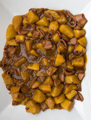 Top view of squid stew with potatoes on a white plate