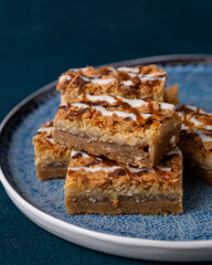 Coconut macaroon cookie bars squares stacked on a dark background