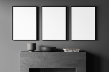 Three empty canvases on dark grey living room wall with fireplace beneath