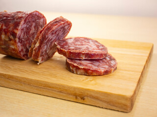 Salami on cutting board. Dried sausage. Traditional Italian salami. Slices of cured sausage on chopping board.