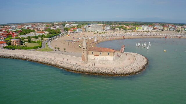 4k drone flight back footage (Ultra High Definition) of Madonna dell'Angelo church - small seaside chapel and pilgrimage destination. Aerial summer cityscape of Caorle town, Italy, Europe.