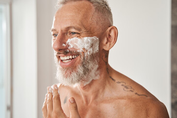 Mature man in shaving foam on bearded face