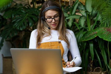 Young home gardener or florist decorator discuss order with new client online work on laptop...