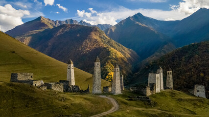 Erzi towers complex in Ingushetia, Russia. Old stone tower complex. Impressive rocky wall of the Caucasus mountains is on the background

