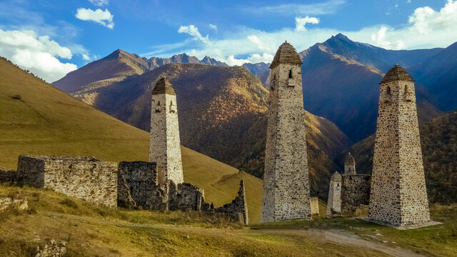 Erzi towers complex in Ingushetia, Russia. Old stone tower complex. Impressive rocky wall of the Caucasus mountains is on the background
