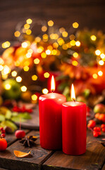 Red candles are lit on a wooden table. Candles surrounded by lights