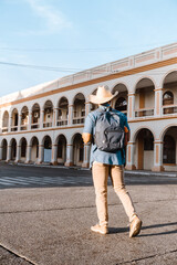 Fototapeta na wymiar Back of man traveler with backpack and hat walking down a street in la ceiba, atlantida honduras.