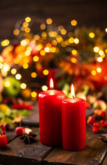 Red candles are lit on a wooden table. Candles surrounded by lights