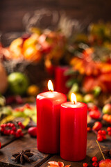 Red candles are lit on a wooden table. Candles surrounded by lights