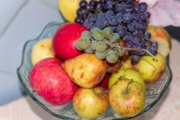 Apples and grapes in a glass dish on the table