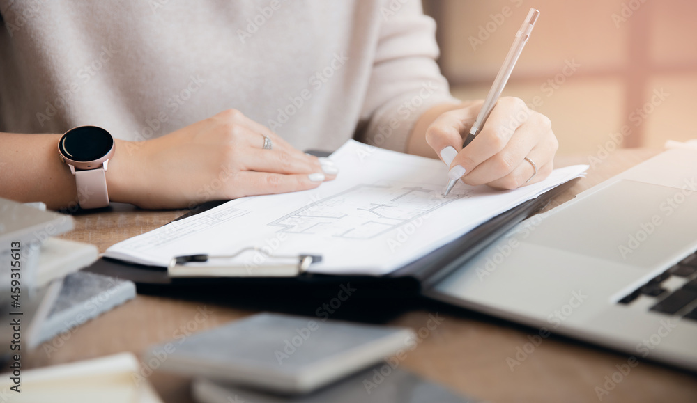 Wall mural Architect draws plan of partitions of apartment, interior designer young woman works at laptop workplace