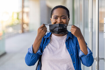 Masked woman - protection against influenza virus. African - American woman wearing mask for protect. Woman wear with protective face mask outdoor. Stop the virus and epidemic diseases.