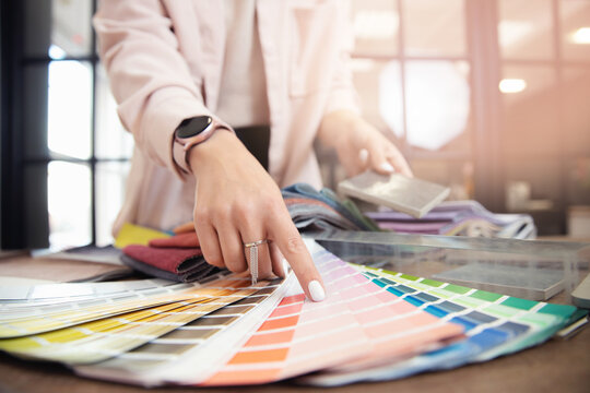 Closeup hand of woman decorator, interior and graphic designer, architect is choosing catalogue colors ral for web project