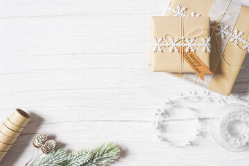 Christmas presents on white wooden background. Winter holiday craft, decoration, brown paper, twine, snowflake ribbon. Sustainable gift wrapping. Double side border. Empty space for text. Copy space.
