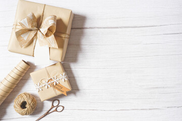 Christmas composition with decoration, presents, scissors, natural paper, twine on white wooden background. Holiday craft gift wrapping. Merry Christmas greetings. Empty space for text. Copy space.