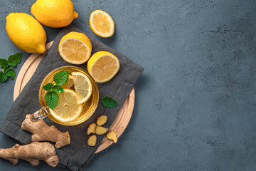 Warming tea with lemon, ginger and mint on a dark background. Top view, copy space.