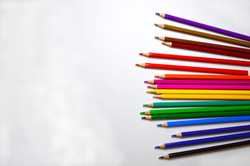 wooden multicolored pencils are lined with a fan in a chaotic order on a white background. art and education development concept