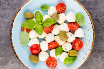 Delicious caprese salad with ripe cherry tomatoes and mini mozzarella cheese balls with fresh basil leaves.