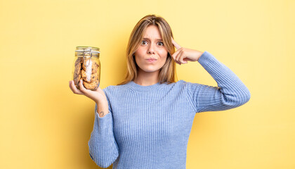 pretty blonde girl feeling confused and puzzled, showing you are insane. homemade cookies concept
