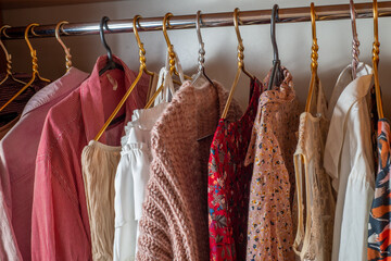 Pink wardrobe. Lots of delicate light summer clothes on hangers in the closet..Decluttering