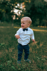 Baby boy in a business suit on a green lawn. Baby's first steps.