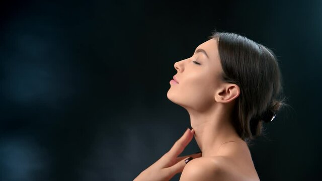 Closeup pleasant brunette Asian woman stroking tender smooth skin neck shoulders enjoy moisturizing