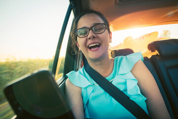 Holidays and tourism concept - smiling teenage girl brunette wearing glasses taking selfie picture with smartphone camera in car
