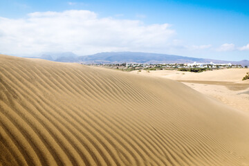 Blue sky and sand dunes with footprints.