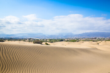 Blue sky and sand dunes with footprints.