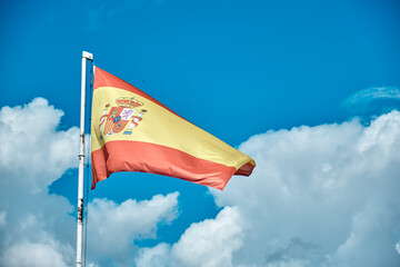 Spanish flag over blue sky with clouds