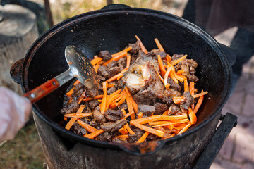 Meat and vegetables are prepared for pilaf. Cooking on an open fire in a cauldron.