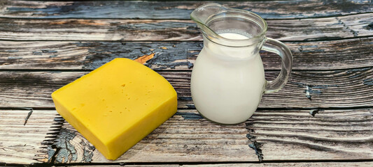 On a wooden background there are a piece of cheese and fresh cream in a decanter. Ukraine,...