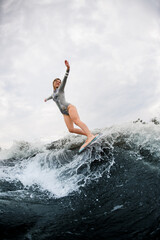 Fabulous view on huge splashing wave and energy woman on wakesurf rides down on it